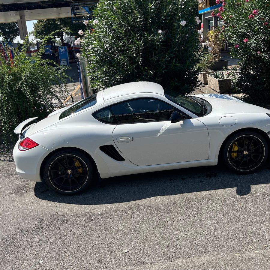 Porsche Cayman bianca vista di lato, con alettone e pinze gialle
